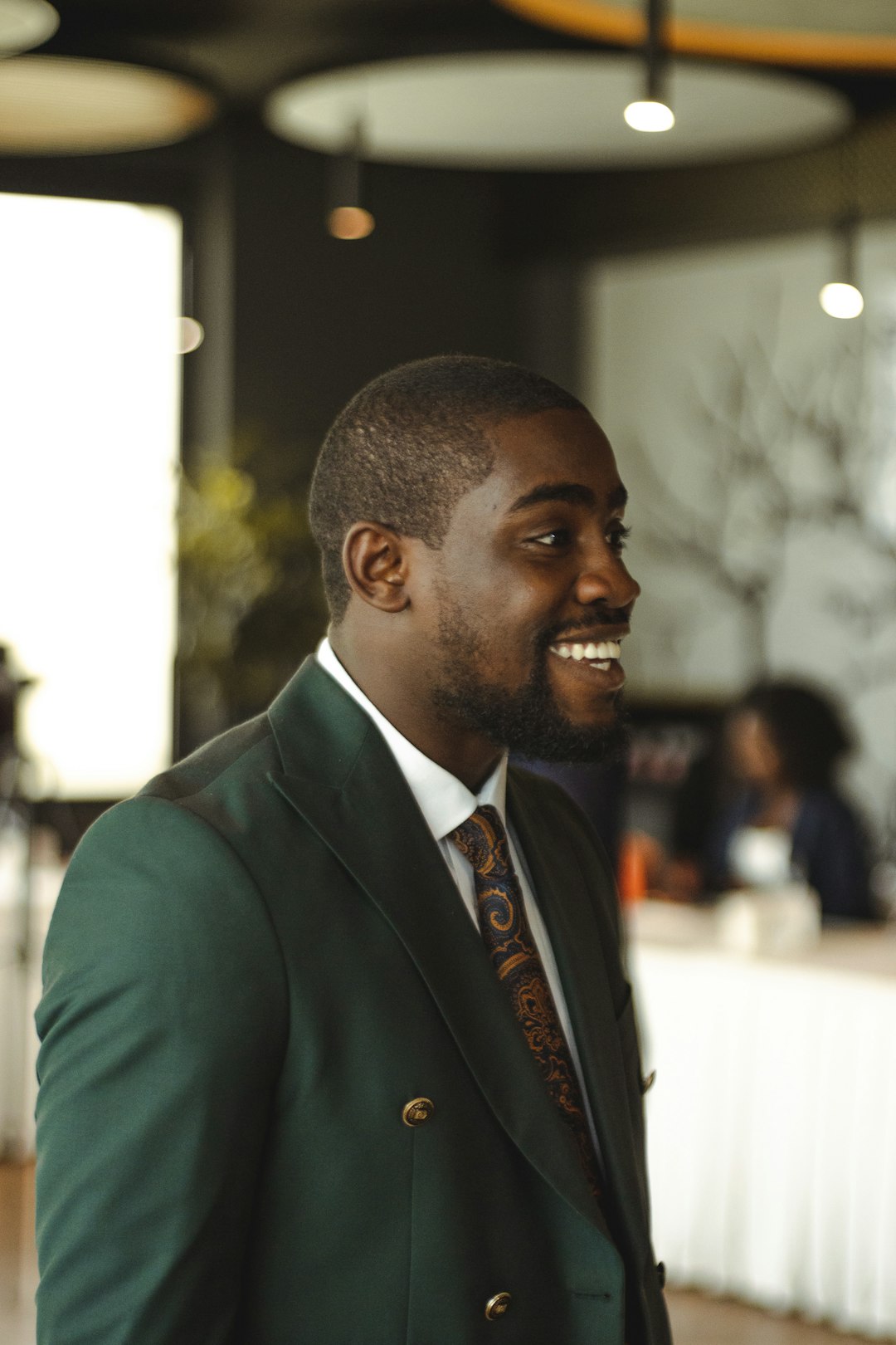 A smiling black man in a green suit.