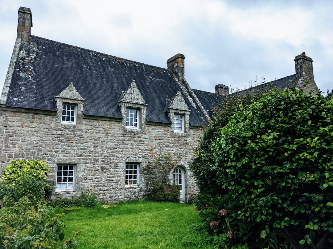 an old stone house with a black roof